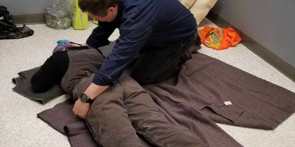 First aid student practicing moving patient into recovery position